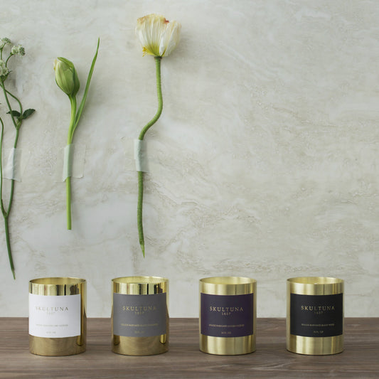 Skultuna Sacred Incense candle shown with other luxury scented candles and flowers on stone wall